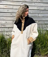 Buzo tipo poncho de polar color crudo con bloque superior en negro y detalles en beige.