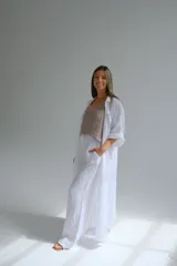 Camisola larga blanca de lino italiano, con corte fluido, cuello camisero, mangas 3/4 con trabilla y dos bolsillos de parche en el pecho.