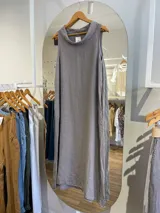 Vestido largo de lino color celeste, sin mangas y con cuello buche. Presenta un diseño de corte holgado con bolsillos laterales.