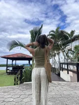 Musculosa verde oliva de morley, translúcida y elástica, con cuello redondo y detalles de costuras expuestas y pequeños dijes metálicos.