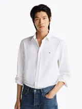 Camisa blanca de corte slim fit, con cuello abotonado, cierre con botones y logo de Tommy Hilfiger bordado en el pecho.