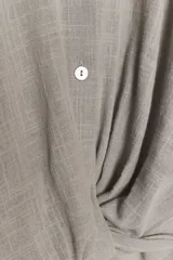 Camisa color gris claro con cuello solapa y escote pico, de manga corta. Presenta un nudo en la parte delantera y cierre frontal con botones.