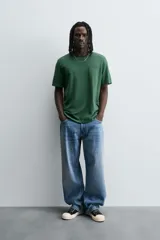 Camiseta verde oscuro de corte relaxed fit, cuello redondo, manga corta y bolsillo plastrón en el pecho.