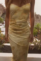 Vestido midi de tul color amarillo pálido con estampado floral, escote redondo y tirantes finos ajustables. Presenta detalle de frunces, forro interior y cierre lateral con cremallera oculta.
