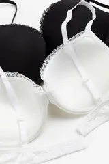 Pack de dos soutiens push-up de microfibra, uno blanco y otro negro, con breteles ajustables, copas acolchadas con aros y ribete de encaje.