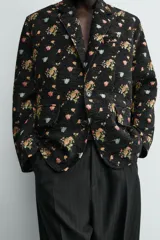 Blazer de hombre de corte relaxed fit confeccionado en tejido jacquard negro con estampado floral multicolor. Tiene cuello con solapas de muesca, manga larga con puños abotonados, bolsillo de vivo en el pecho, bolsillos de solapa en la cadera, bolsillo interior, abertura en el centro de la espalda y cierre frontal con botones.