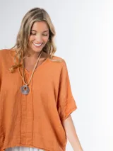 Remerón tipo poncho color naranja confeccionado en lino italiano, con escote en V y bolsillos laterales.