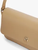 Cartera mensajera color beige con monograma TH dorado en el frente. Tiene asa superior, correa de textil trenzado ajustable y extraíble, bolsillo interior con cremallera y monedero extraíble con cremallera.