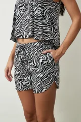 Short negro de tiro alto con cordón ajustable en la cintura y bolsillos laterales. Presenta un corte holgado y ruedos redondeados.