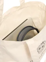 Bolso tote de lona color crema con logo Under Armour Athletics estampado en negro.