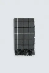 Bufanda gris con diseño a cuadros en blanco, marrón y negro, con flecos en los extremos.