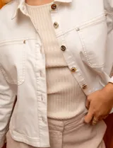 Campera de denim blanca con cuello con solapa, abertura central con botones metálicos y bolsillos delanteros.