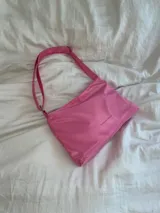 Cartera de lona semi impermeable color lila, con cierre metálico, forrería de gross y bolsillo interno. Tiene tira regulable para usar colgada al hombro, cruzada o como riñonera.