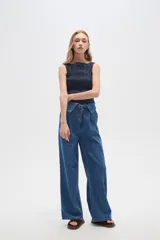 Pantalón jean de tiro alto color azul, con pinzas en la cintura, corte ancho y cierre frontal con botón y cremallera.