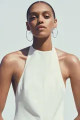 Mono largo blanco de cuello halter con botones y espalda descubierta. Pierna ancha y cierre trasero con cremallera oculta.