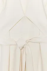 Vestido midi color crudo, con escote en V y mangas largas acampanadas. Cintura ajustable con lazos del mismo tejido.