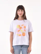 Remera blanca de corte recto con estampado de frutas cítricas y texto en color rosa.