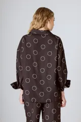 Camisa marrón con estampado de círculos blancos, cuello mao, manga larga y cierre frontal con botones.