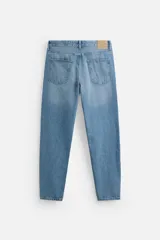 Pantalón de jean celeste de corte slim fit y tapered, con cinco bolsillos, efecto lavado y cierre frontal con cremallera y botón.