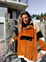 Buzo de terciopelo color tostado, beige y negro, con cierre de media cremallera, cuello alto con botones a presión y bolsillo tipo canguro con solapa y botón.
