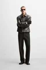 Pantalón negro de corte recto con cintura elástica, bolsillos delanteros y traseros. Cierre frontal con cremallera y botón.