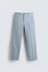 Pantalón de vestir celeste claro, corte slim fit, con bolsillos laterales y traseros de doble vivo con botón. Cierre frontal con cremallera y botón.