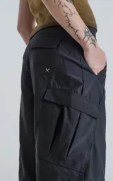 Pantalón negro con corte ancho, bolsillos laterales con solapa y detalle de cierre a la altura de la rodilla para convertirlo en short.