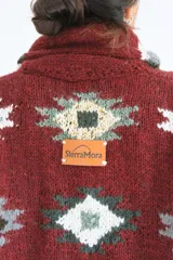 Saco tejido a mano de lana color azul marino con diseño geométrico multicolor. Tiene cuello tipo chal y cierre frontal con botones.