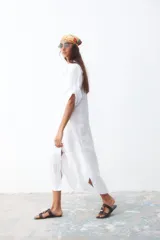 Vestido camisero midi blanco de lino con cuello camisero, mangas cortas con dobladillo y cierre frontal con botones.
