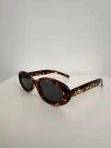 Lentes de sol con marco ovalado de carey y cristales oscuros, con protección UV400.