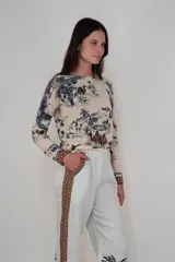 Sweater de cashmere color beige con estampado de paisaje con camellos, palmeras y aves en tonos azul y marrón.