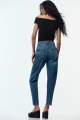 Jeans de tiro alto color celeste, corte mom fit, con cinco bolsillos y cierre frontal con cremallera y botón.