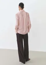 Camisa celeste con rayas verticales finas, de tejido fluido, manga larga abotonada, cuello camisero y corte recto.