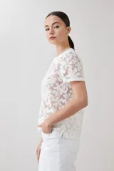 Blusa blanca de encaje con mangas cortas y cuello redondo.