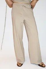 Pantalón de algodón color beige, de corte amplio y tiro alto, con cintura elástica ajustable con cordones y bolsillos laterales.
