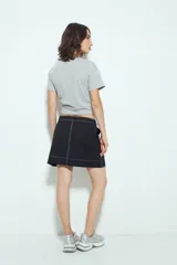 Falda corta tipo cargo de tiro medio, color negro, con costuras visibles en contraste blanco y bolsillos aplicados.