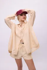 Camisa blanca de lino y algodón, con cuello clásico, cierre frontal con lazos y mangas largas abullonadas con puños ajustables con lazos.