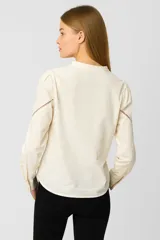 Blusa color blanco con cuello mao, manga larga con puños abotonados, cierre frontal con botones ocultos y detalle de bordado con strass en el canesú.