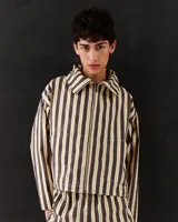 Chaqueta corta de gabardina de algodón a rayas verticales en tonos beige y negro. Tiene cuello alto, cierre metálico frontal, bolsillos laterales y está totalmente forrada.