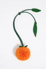 Charm para cartera color blanco con forma de fruta naranja con hojas verdes.