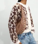 Bolso de hombro tipo hobo color borgoña, con apliques de tachas plateadas y asa corta.