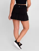Falda deportiva negra con calza interior, de secado rápido. Diseño acampanado con plisado en la parte trasera, pretina ancha con bolsillo con cierre y bolsillo interior en la calza.