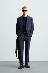 Blazer regular fit de hombre confeccionado en tejido con lana. Cuello con solapas de muesca, manga larga con puño abotonado, bolsillo de vivo en pecho, bolsillos de solapa en cadera, bolsillo interior, bajo con aberturas en espalda y cierre frontal de botonadura.