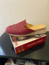 Mules de cuero color rojo con diseño de sol bordado.