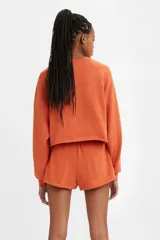 Conjunto deportivo Levi's color naranja, compuesto por un sweater corto con logo estampado en el pecho y shorts de cintura alta con ruedo desflecado.
