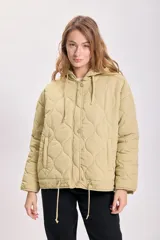 Campera capitoneada color verde claro, con capucha y cierre frontal con botones a presión. Tiene bolsillos laterales y cordón ajustable en el ruedo.