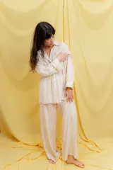 Conjunto color beige compuesto por una camisa oversize de manga larga con botones frontales y bolsillo en el pecho, y un pantalón amplio con cintura elástica.