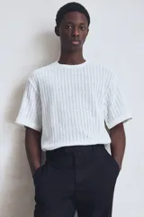 Remera blanca de punto calado con textura tipo crochet, corte estándar, cuello redondo y mangas cortas.