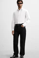 Camisa blanca de corte slim fit, confeccionada en algodón, con cuello italiano, mangas largas con puños abotonados y cierre frontal con botones.