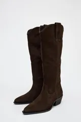 Bota alta de caña alta color marrón chocolate, de serraje con puntera fina y taco bajo.